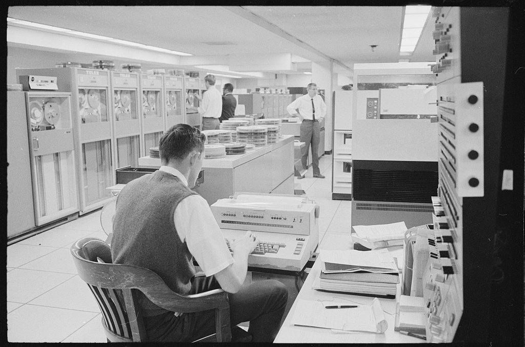 Public domain photograph of a government computer room with rows of equipment and operators.